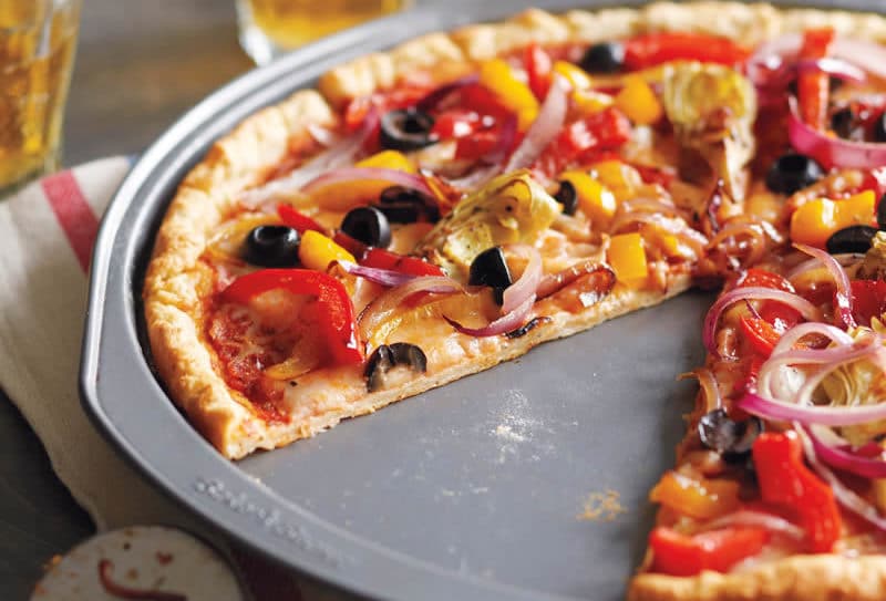 Overhead shot of a thin crust pizza topped with a variety of colorful vegetables.