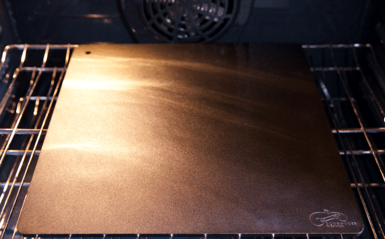 A steel pizza pan inside an oven.